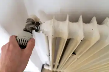 Bavaria, Germany - March 17, 2024: Hand turns the thermostat of a radiator