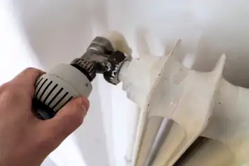 Bavaria, Germany - March 17, 2024: Hand turns the thermostat of a radiator