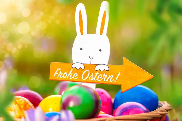 March 19, 2024: Happy Easter! Greeting on a signpost sign held by a wooden Easter bunny in an Easter nest with colorful eggs in the sunshine. PHOTOMONTAGE