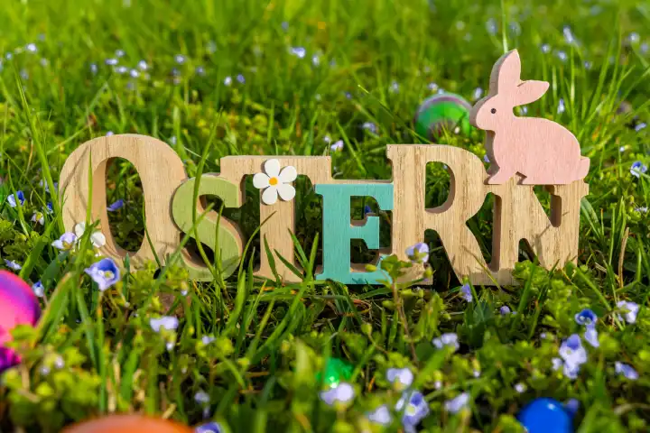 Augsburg, Bavaria, Germany - 19 March 2024: Easter, wooden lettering in a green meadow with colorful eggs