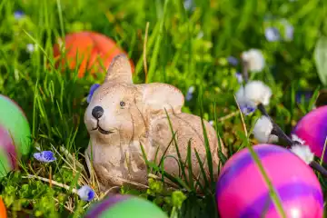 Augsburg, Bavaria, Germany - 19 March 2024: Easter bunny sits in green meadow with colorful Easter eggs