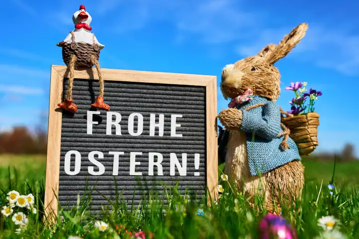 Augsburg, Bavaria, Germany - March 25, 2024: Happy Easter! Greeting on a board held by an Easter bunny in a green meadow with colorful Easter eggs. PHOTOMONTAGE