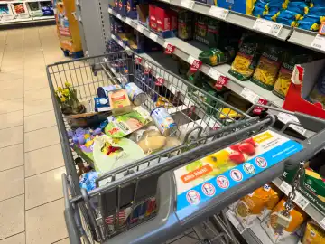 Themenbild Einkaufen an Ostern, Ein Einkaufswagen voller Lebensmittel und Ostersüßigkeiten zum Osterfest in einem Supermarkt