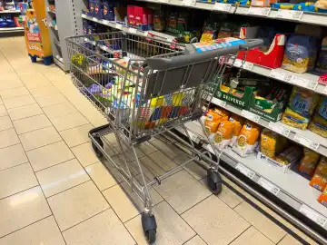 Themenbild Einkaufen an Ostern, Ein Einkaufswagen voller Lebensmittel und Ostersüßigkeiten zum Osterfest in einem Supermarkt