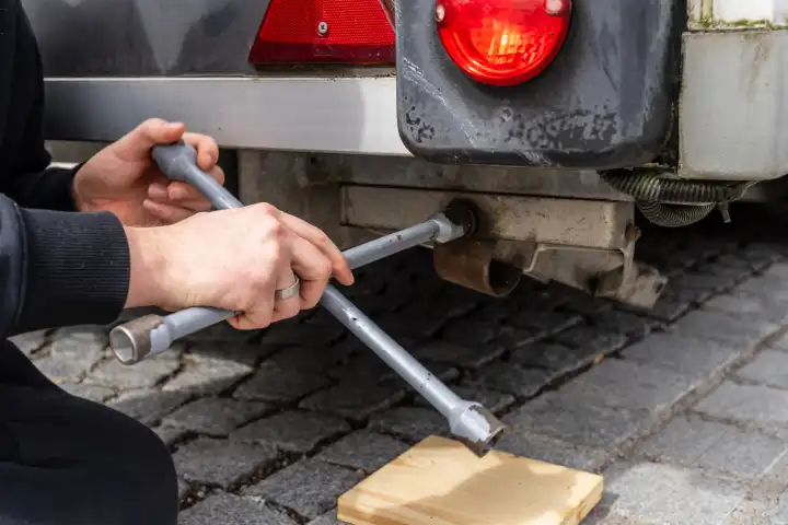 Schwabmünchen, Bavaria, Germany - March 17, 2024: Man twists a leg off a trailer with a cross wrench