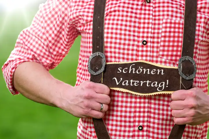 Schönen Vatertag! Gruß auf der Lederhose von einem Mann in bayerischer Tracht. FOTOMONTAGE