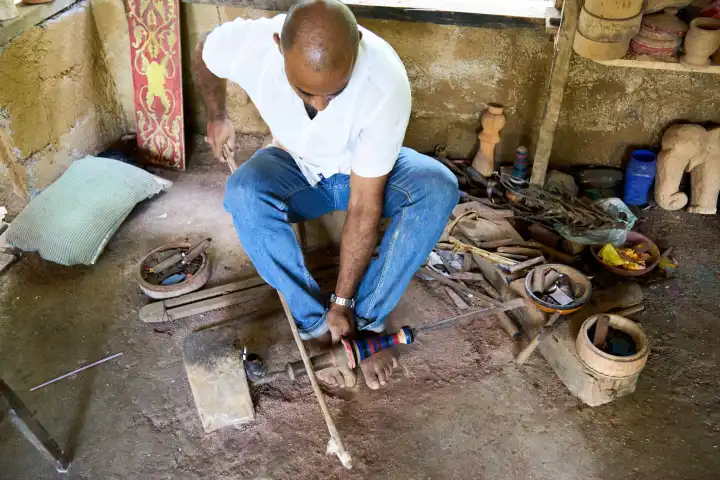 Sri Lanka, Asia - December 21, 2023: A man makes wooden sculptures using traditional woodworking techniques with a bow-foot drill in the workshop in Sri Lanka
