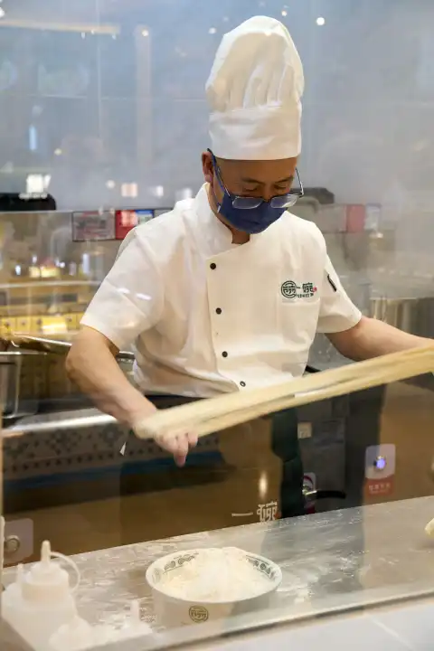 Ein Koch in einer Küche stellt Handgezogene Ramen-Nudeln her