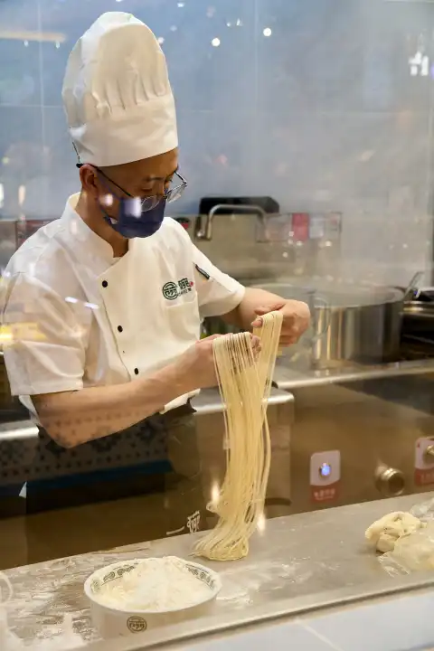 Kuala Lumpur, Malaysia - December 27, 2023:  A cook in a kitchen makes hand-pulled ramen noodles