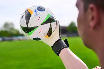 Themenbild: EURO 2024 offizieller Fußball Spielball von Sportausrüster Adidas. Spieler hält Ball auf einem Fußballfeld. Fußball-Europameisterschaft 2024