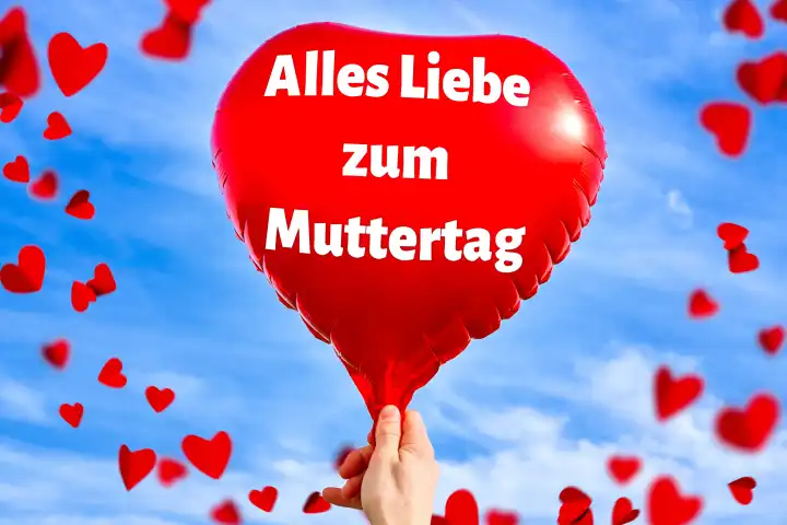 Alles Liebe zum Muttertag! Gruß zum Muttertag, auf einem roten Ballon in Herzform vor blauem Himmel mit roten kleinen Herzen. FOTOMONTAGE