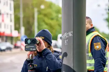 Augsburg, Bavaria, Germany - April 17, 2024: Speed measurement by the Augsburg police on the occasion of the 2024 speed camera marathon. Policewoman with laser measuring device on a road