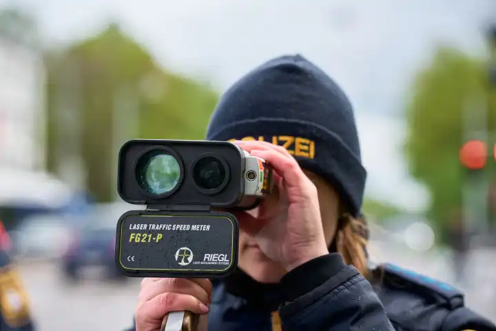 Augsburg, Bavaria, Germany - April 17, 2024: Speed measurement by the Augsburg police on the occasion of the 2024 speed camera marathon. Policewoman with laser measuring device on a road