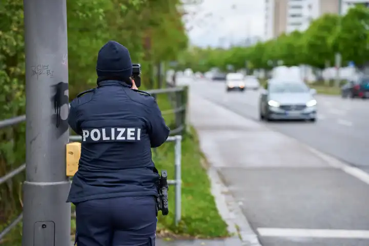 Geschwindigkeitsmessung der Polizei Augsburg anlässlich zum Blitzermarathon 2024. Polizistin mit Lasermessgerät an einer Straße