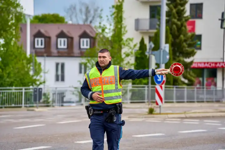 Augsburg, Bavaria, Germany - April 17, 2024: Cross-state safety day for Speedweek or speed camera marathon in Augsburg. Police officer stops a vehicle on the road with a police trowel