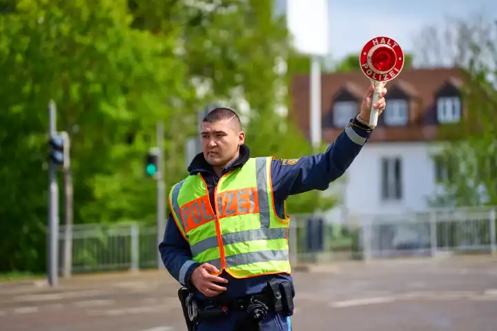 Länderübergreifender Sicherheitstag zur Speedweek bzw. Blitzermarathon in Augsburg. Polizist hält mit einer Polizeikelle auf der Straße ein Fahrzeug auf