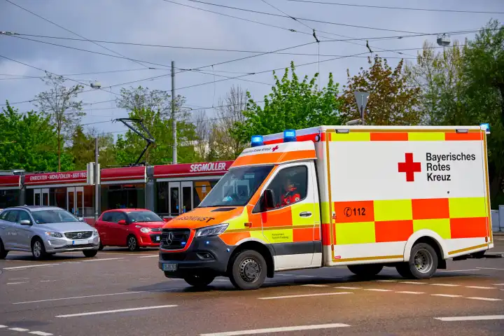 Rettungswagen des Bayerischen Roten Kreuz fährt mit Blaulicht durch die Stadt zu einem Rettungseinsatz