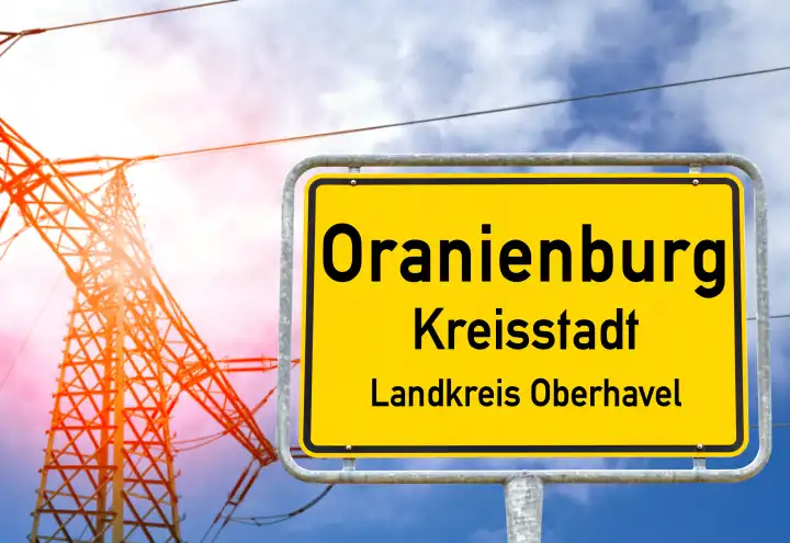 18 April 2024: Oranienburg town sign in front of an electricity pylon. Symbolic image of electricity and power connection problem in Oranienburg. PHOTOMONTAGE