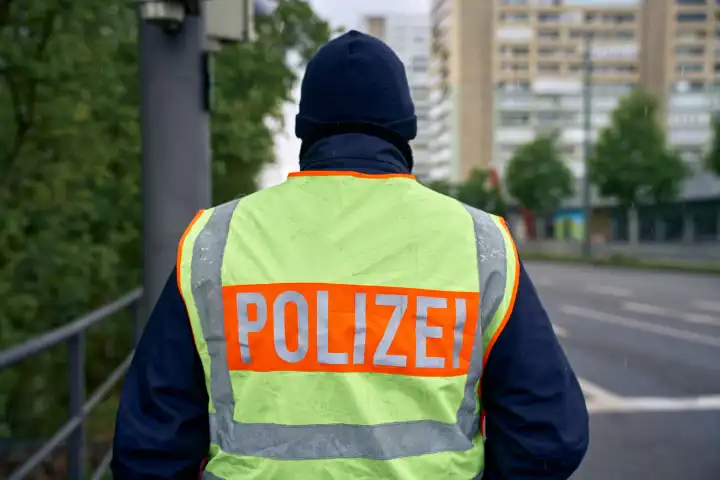 Polizist in Uniform mit einer Warnweste und der Aufschrift Polizei