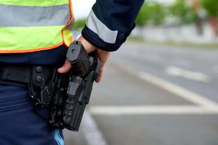 Polizist in Polizei Uniform hält die Hand an der Waffe