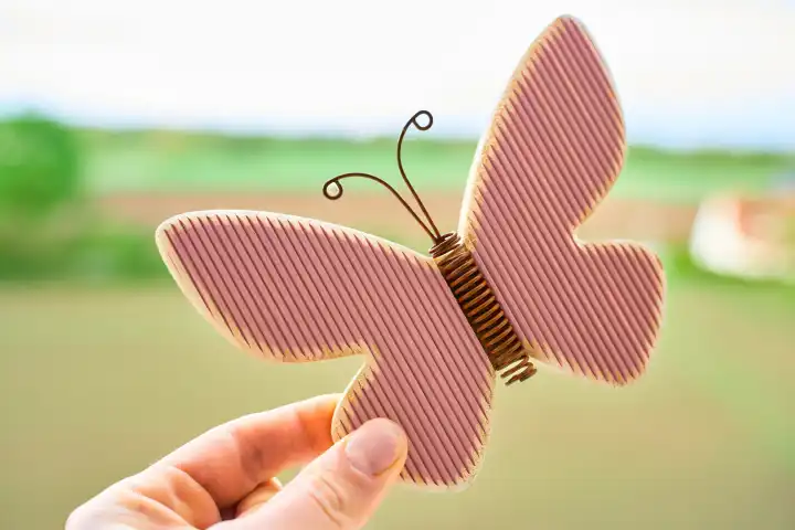 Hand hält einen Schmetterling aus Holz. Symbolbild Frühling. Frühlingsdeko