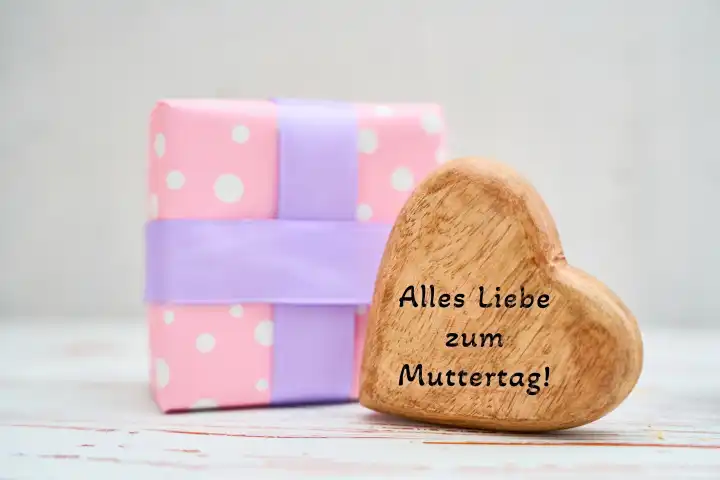Augsburg, Bavaria, Germany - April 17, 2024: All the best for Mother's Day! Greeting for Mother's Day, on a wooden heart next to a gift. PHOTOMONTAGE