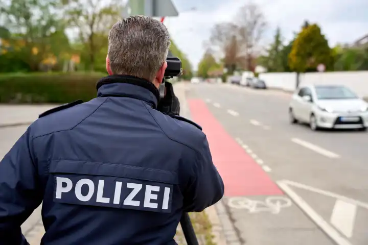 Themenbild Blitzermarathon in Bayern. Radarkontrolle der Polizei in Augsburg. Ein Polizist misst die Geschwindigkeit mit einem Laser Messgerät in einer 30 Km/h Zone