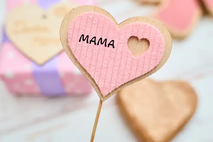 Herz aus Holz mit der Aufschrift: Mama, vor einem Geschenk. FOTOMONTAGE