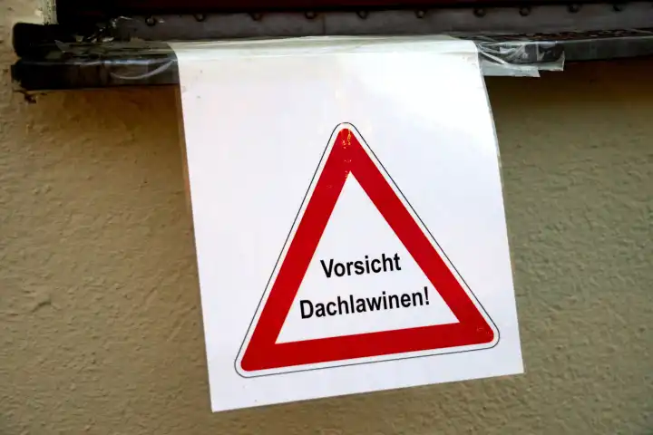 Schild an einer Hauswand mit der Warnung: Vorsicht Dachlawinen!