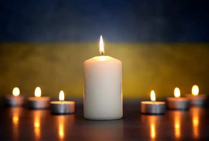 Brennende Kerzen vor einer Ukraine Flagge. Symbolfoto Trauer um die gefallenen Soldaten und Zivilisten im Russland Ukraine Krieg. FOTOMONTAGE