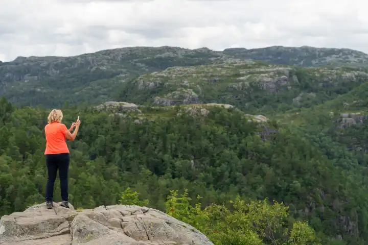 Frau macht in Norwegen mit dem Handy ein Foto von der Natur