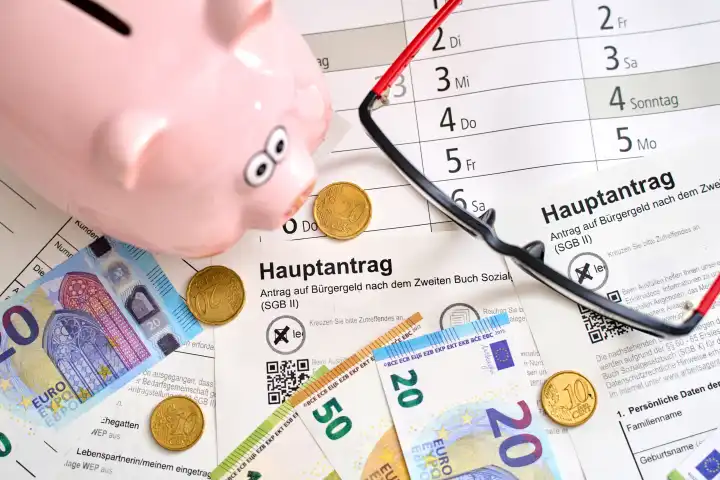 Augsburg, Bavaria, Germany - April 25, 2024: Main application for citizen's allowance from the employment agency spread out with euro banknotes, glasses and piggy bank. Social welfare