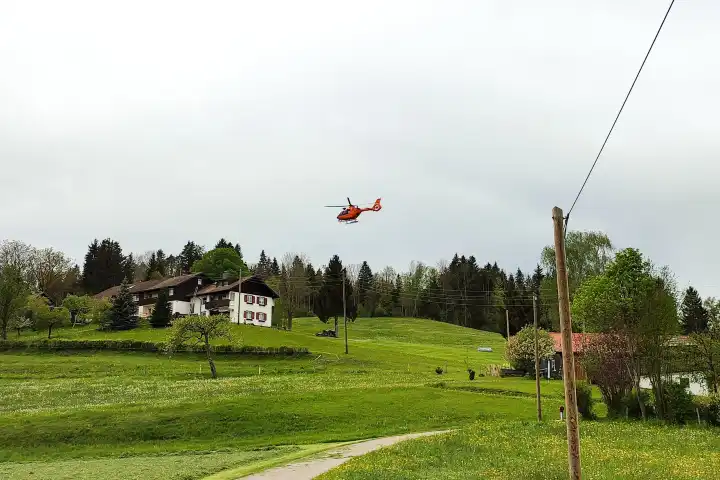 Waltenhofen, Bavaria, Germany - April 28, 2024: Christoph 17 rescue helicopter of the Kempten Mountain Rescue Service in action in the Allgäu in the mountains near the highway