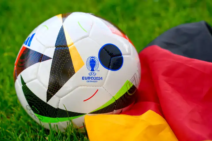 Symbolbild UEFA EURO 2024 offizieller Fußball Spielball von Sportausrüster Adidas auf einem Fußballfeld mit Deutschland Flagge. Fußball-Europameisterschaft 2024 