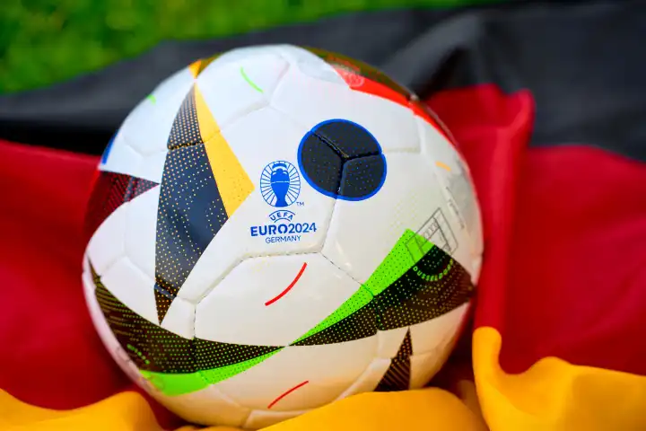 Symbolbild UEFA EURO 2024 offizieller Fußball Spielball von Sportausrüster Adidas auf einem Fußballfeld mit Deutschland Flagge. Fußball-Europameisterschaft 2024 