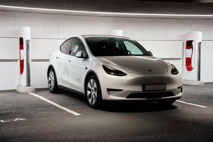 Tesla Model Y an einem Tesla Supercharger. Ladesäule zum Schnelladen von E-Autos
