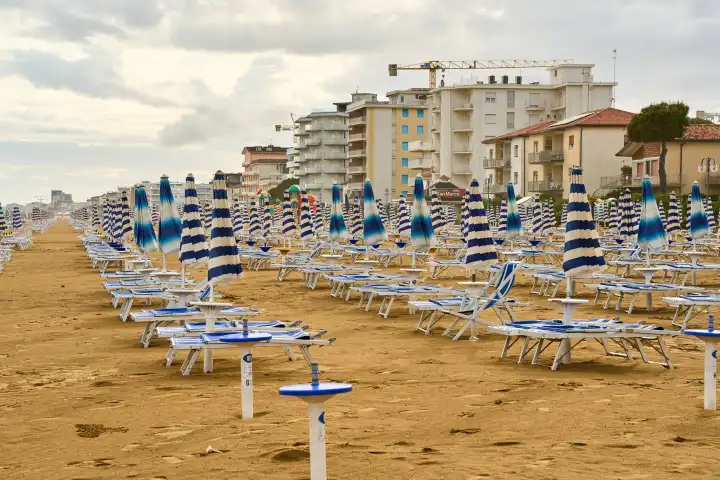 Lido di Jesolo, Italy - 2 May 2024: Closed umbrellas on the beach of Lido di Jesolo in Italy