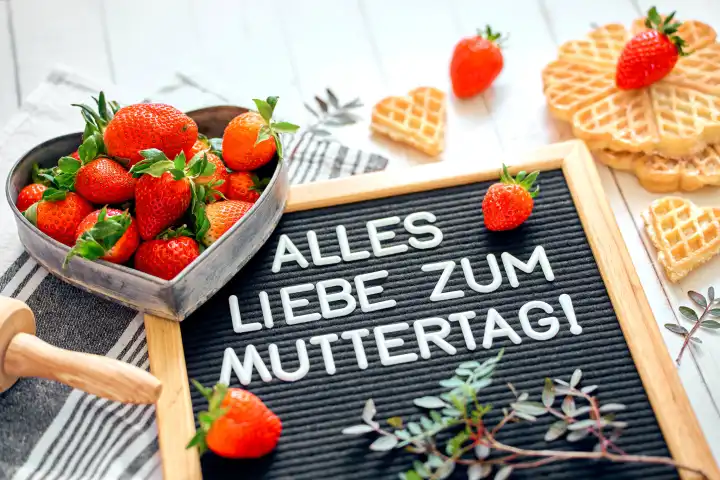 10 May 2024: All the best for Mother's Day! Mother's Day greeting, lettering on a blackboard surrounded by fresh red strawberries and baked waffles. Mother's Day, symbolic image