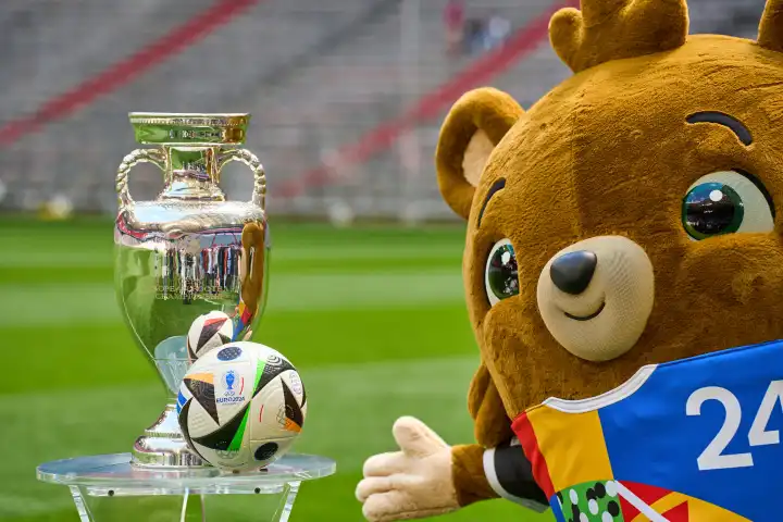 Themenbild Fußball EURO 2024: Maskottchen der Europameisterschaft Albärt steht auf dem Spielfeld der Allianz Arena zusammen mit dem offiziellen Spielball von Adidas und dem Henri-Delaunay-Pokal der UEFA EURO 2024
