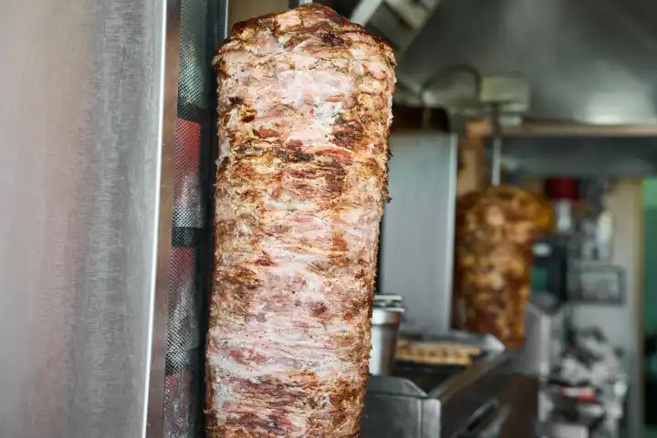 Ein Döner Kebab Fleischspieß an hängt an einem Grill in einem Restaurant bzw Imbiss
