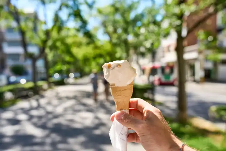 Hand hält ein Eis in einer Waffel an einem sonnigen Sommertag