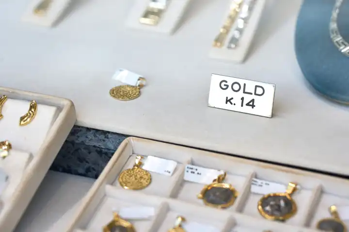 Goldschmuck wie Ketten und Armbänder in dem Schaufenster von einem Juwelier mit einem Schild mit der Aufschrift 14 Karat Gold 