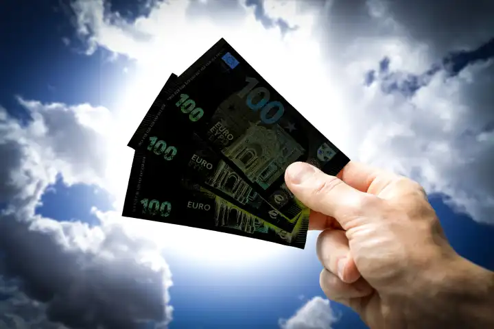 Hand hält drei schwarze 100-Euro-Scheine in die Luft, Symbol für Schwarzgeld, FOTOMONTAGE
