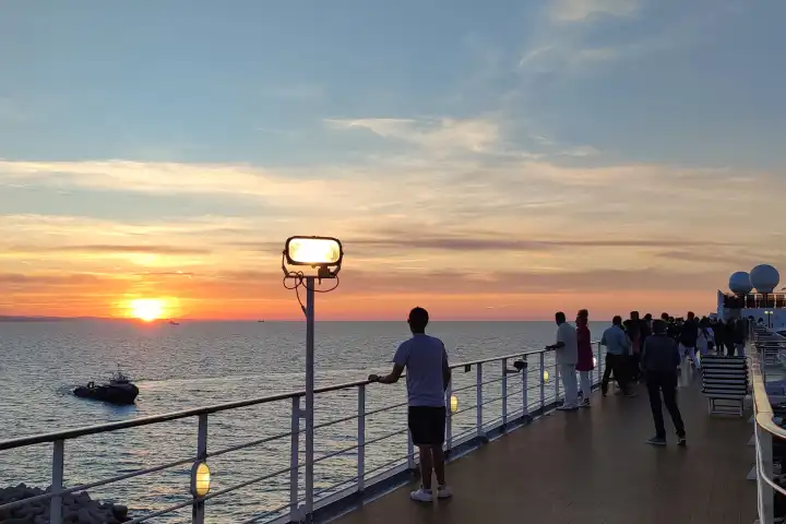 Passagiere genießen den Sonnenuntergang in Ihrem Urlaub von einem Kreuzfahrtschiff und blicken auf das Meer