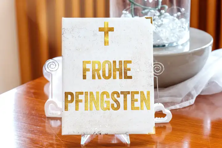 Frohe Pfingsten - Gruß auf einem weißen Buch mit einem Kreuz. FOTOMONTAGE
