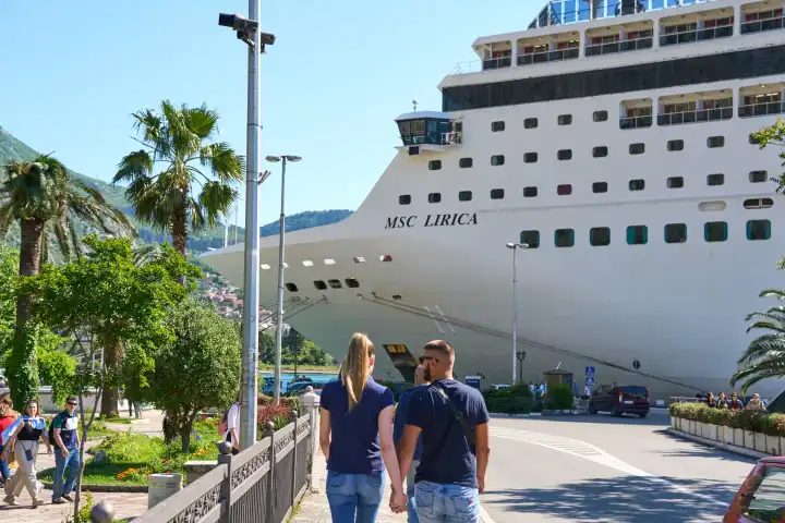 verliebtes junges Paar läuft an der Promenade von Kotor in Montenegro entlang und blickt auf das Kreuzfahrtschiff MSC Lirica