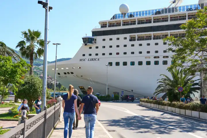 verliebtes junges Paar läuft an der Promenade von Kotor in Montenegro entlang und blickt auf das Kreuzfahrtschiff MSC Lirica