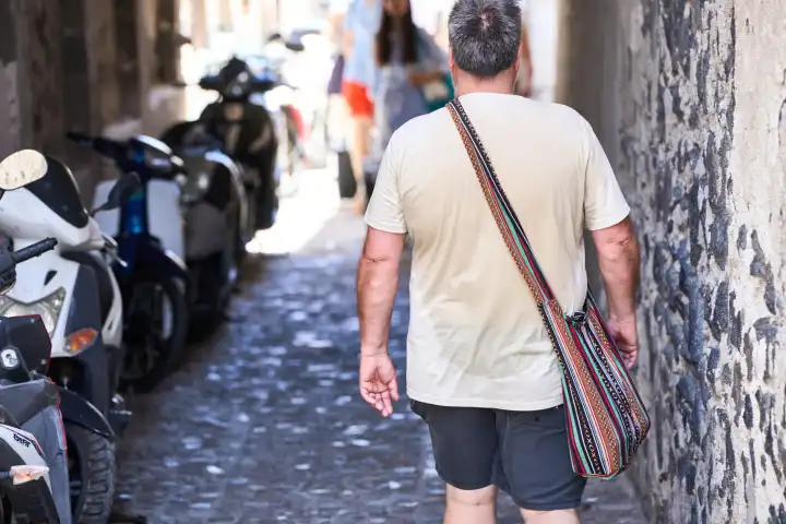 Übergewichtiger Mann mit nass geschwitztem T-Shirt im Sommer. Nasser Rücken durch Hitze 