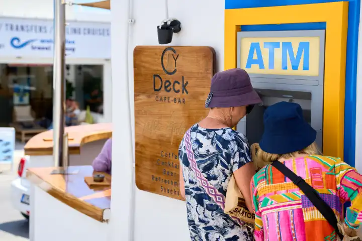 Zwei Damen heben Bargeld an einem Geldautomaten ATM in der Stadt Thira auf Santorini in Griechenland ab. Symbolbild Bargeldabhebung im Ausland