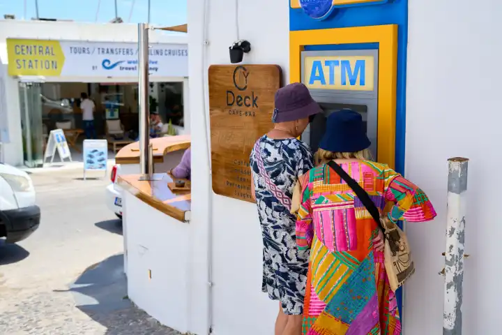 Zwei Damen heben Bargeld an einem Geldautomaten ATM in der Stadt Thira auf Santorini in Griechenland ab. Symbolbild Bargeldabhebung im Ausland